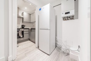 A modern kitchen with a white refrigerator, a kettle, and a built-in oven. - Central - Stay 2 - Paid Parking - Near Transport (Maidstone)