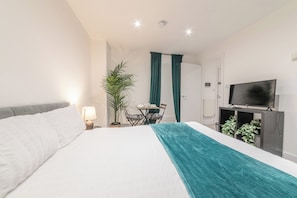 A hotel room with a bed, a desk, a chair, a TV, and a plant. - Central - Stay 2 - Paid Parking - Near Transport (Maidstone)
