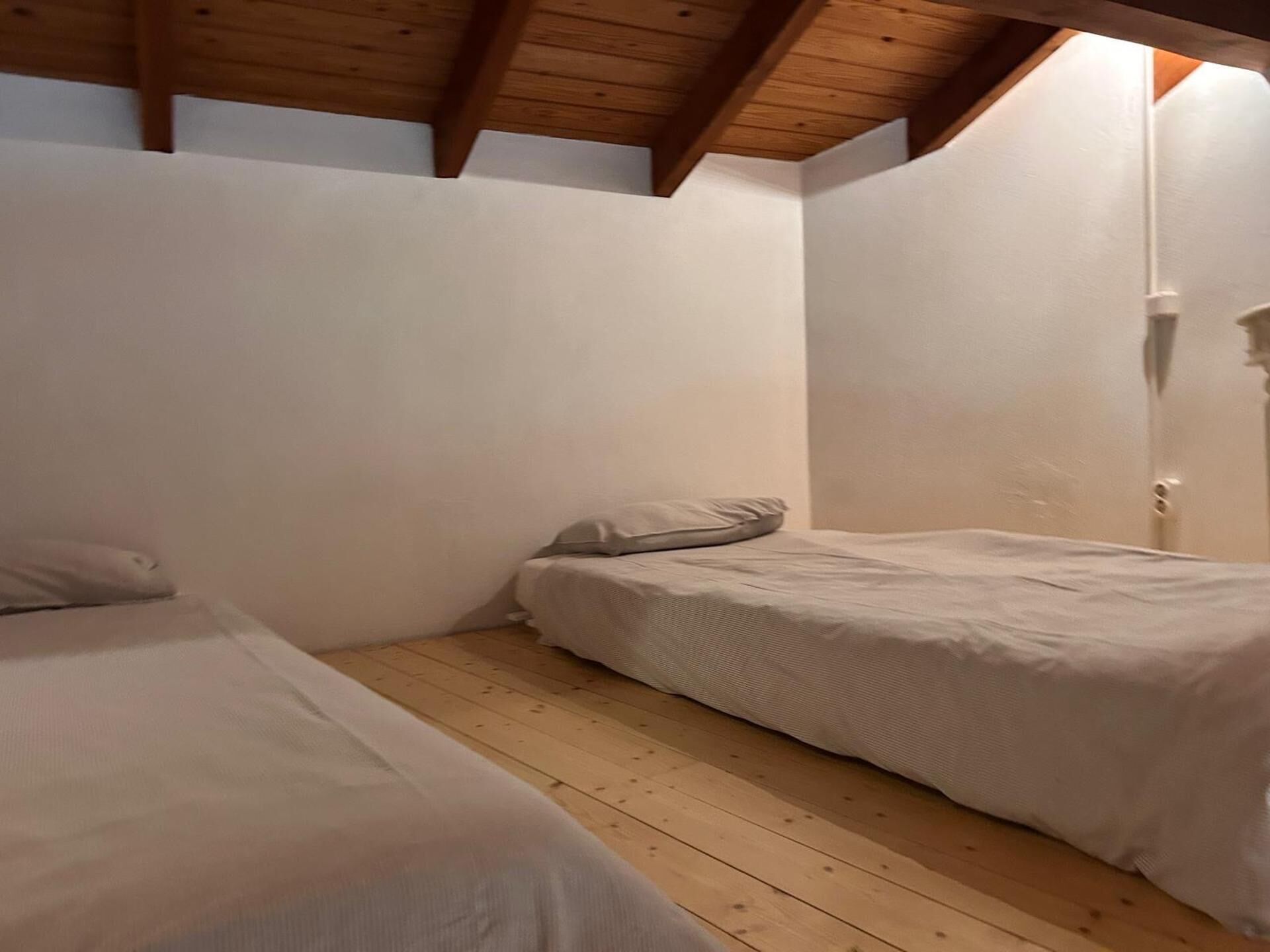 A bedroom with two single beds, wooden flooring, and a sloped ceiling.