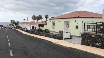Una calle costera con una hilera de casas, un muro de piedra y una reja.