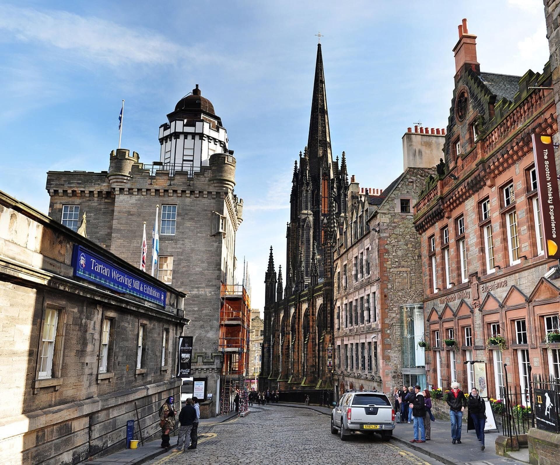 A historic street with a prominent church spire, a weaving mill, and a whisky distillery.