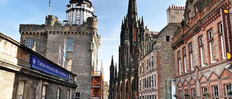 A historic street with a prominent church spire, a weaving mill, and a whisky distillery.