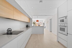 A modern kitchen with a kettle, a coffee maker, and a built-in oven.