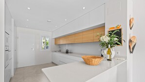 Una cocina moderna con armarios blancos, encimera de madera y una cesta en la isla.