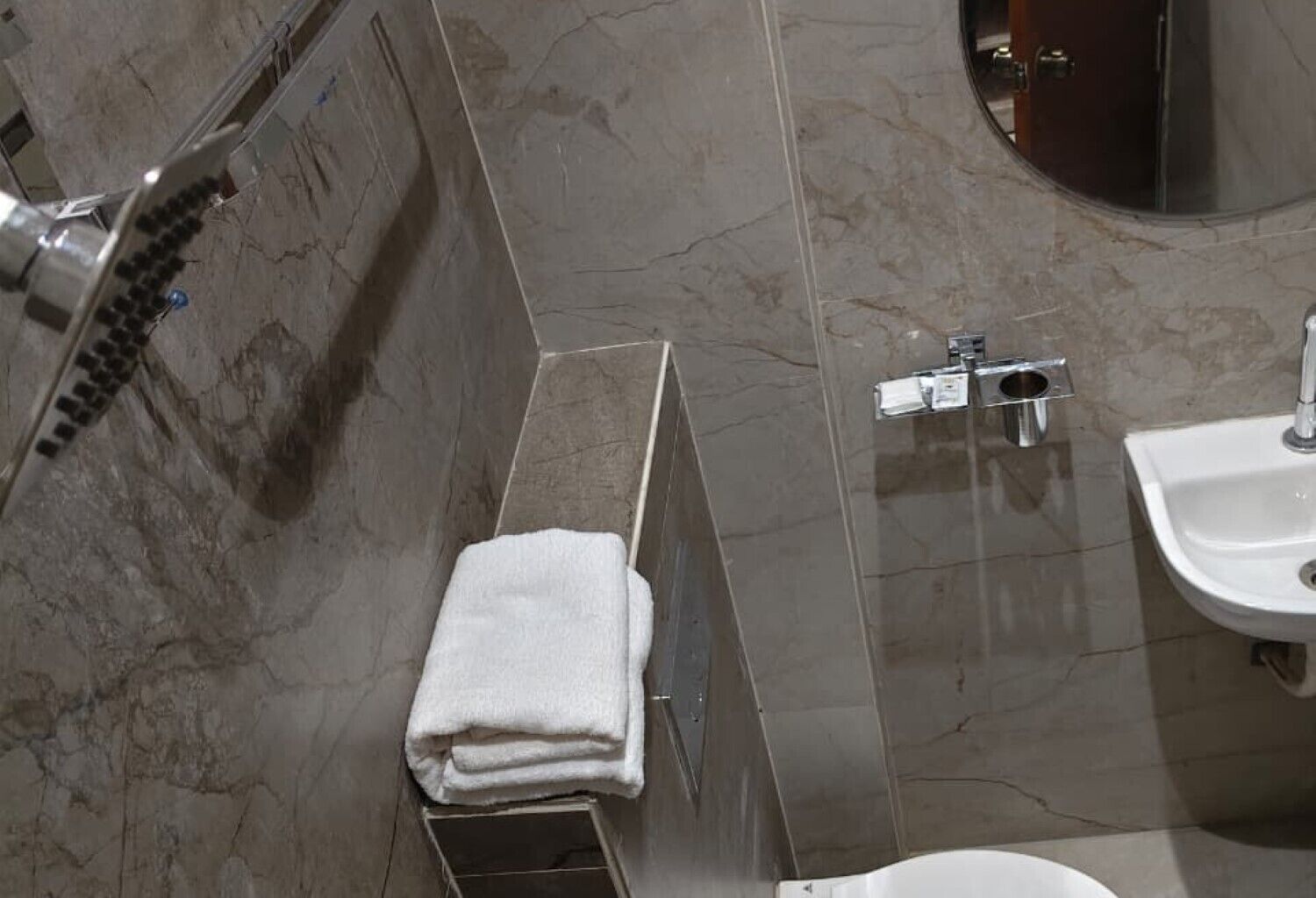 A bathroom with a shower, a sink, and a towel rack.