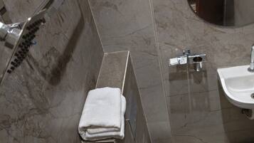 A bathroom with a shower, a sink, and a towel rack.