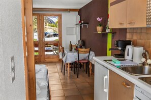 A kitchen with a dining area, a coffee machine, and a view of the outside. - Convenient studio with view in the center of the resort (Anniviers)