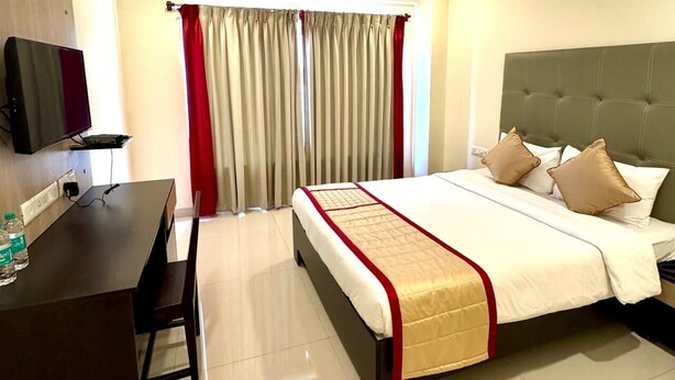 Ein Hotelzimmer mit Bett, Schreibtisch, Fernseher und Deckenventilator.