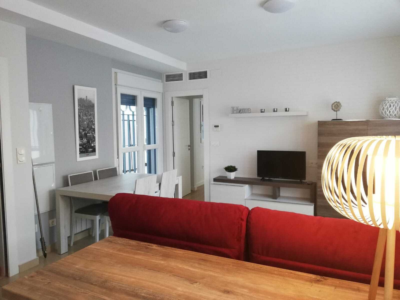Une cuisine moderne avec un coin repas, un téléviseur et un canapé rouge.