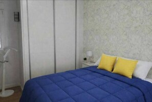 Una camera da letto con un letto, un comodino e una lampada a parete.