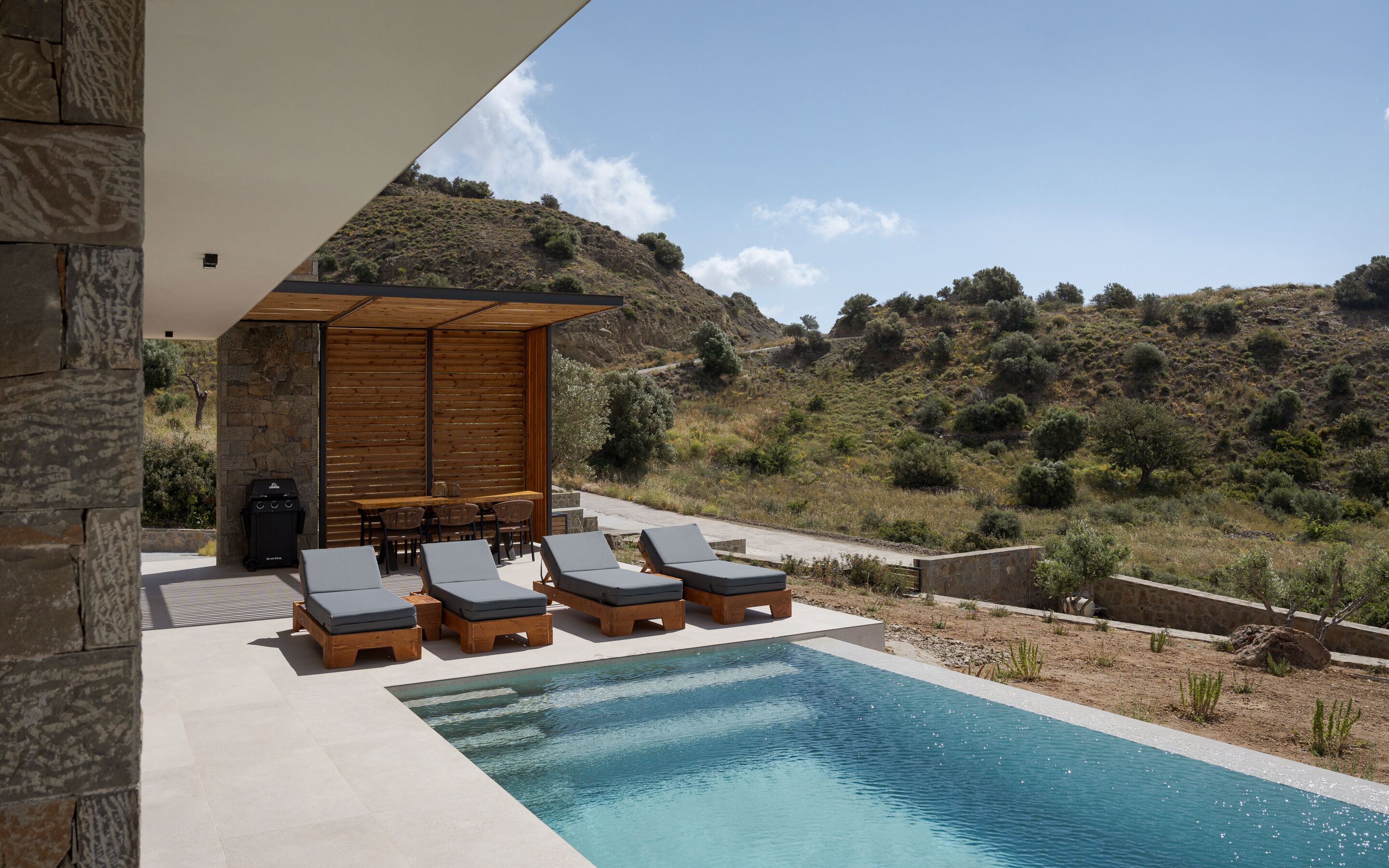 A pool area with lounge chairs and a barbecue grill.