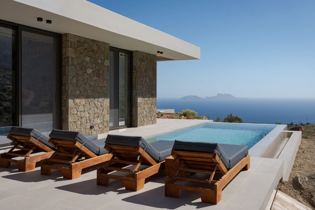 A modern poolside area with lounge chairs and a view of the ocean.