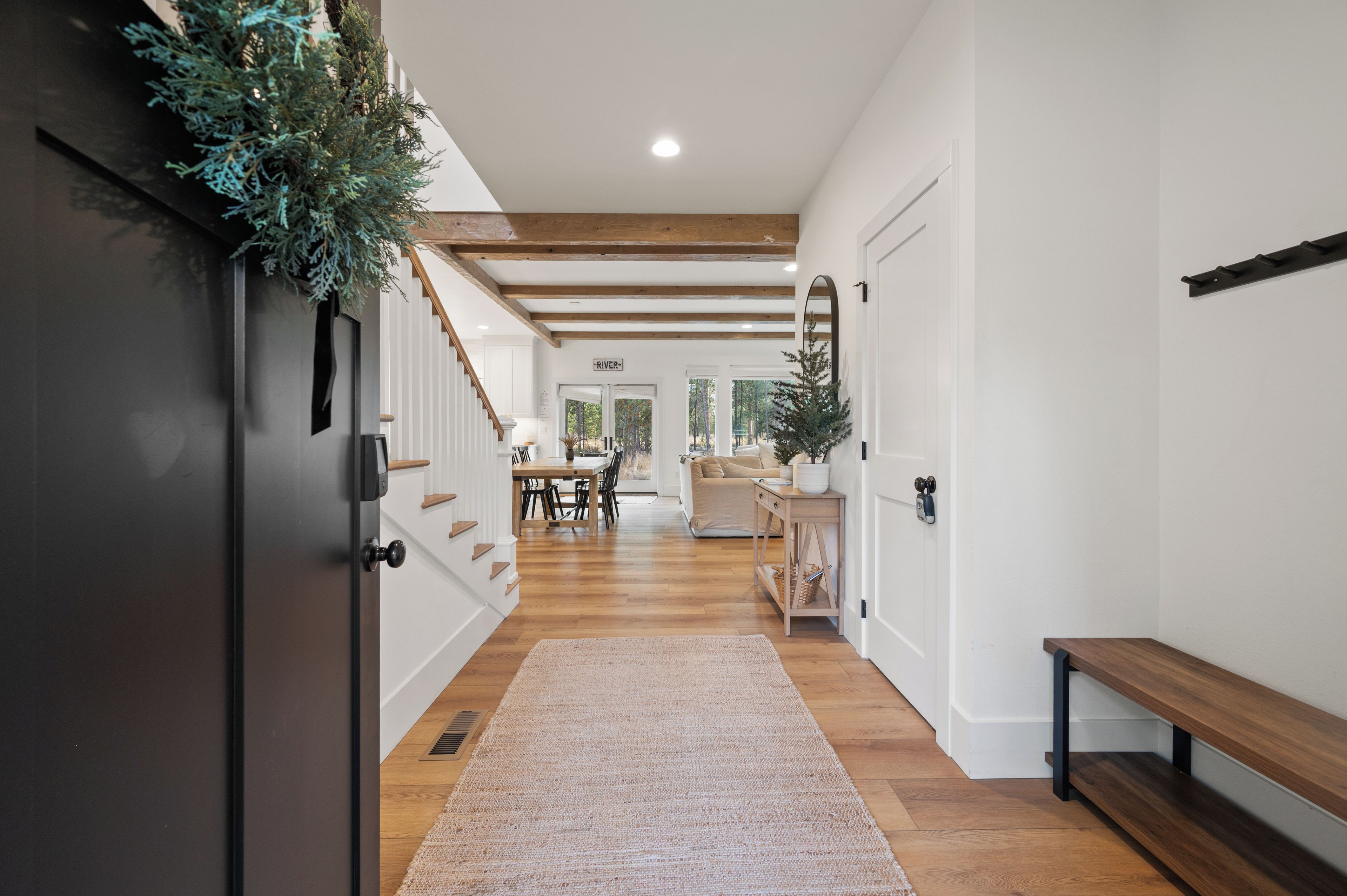 A hallway with a wooden bench, a rug, and a door with a plant decoration.