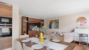 Ein modernes Wohnzimmer mit Essbereich, Holzausstattung, einem Gemälde und einem weißen Sofa.