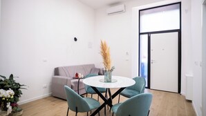 A modern living room with a round table, four chairs, a sofa, and a door leading to another room. - Cozy house 2 minutes from Reggio Calabria Cathedral and Via Marina (Reggio Calabria)