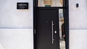 A black door with a handle and a keyhole, a sign above it, and a reflection of a building and a car in the glass. - Cozy house 2 minutes from Reggio Calabria Cathedral and Via Marina (Reggio Calabria)