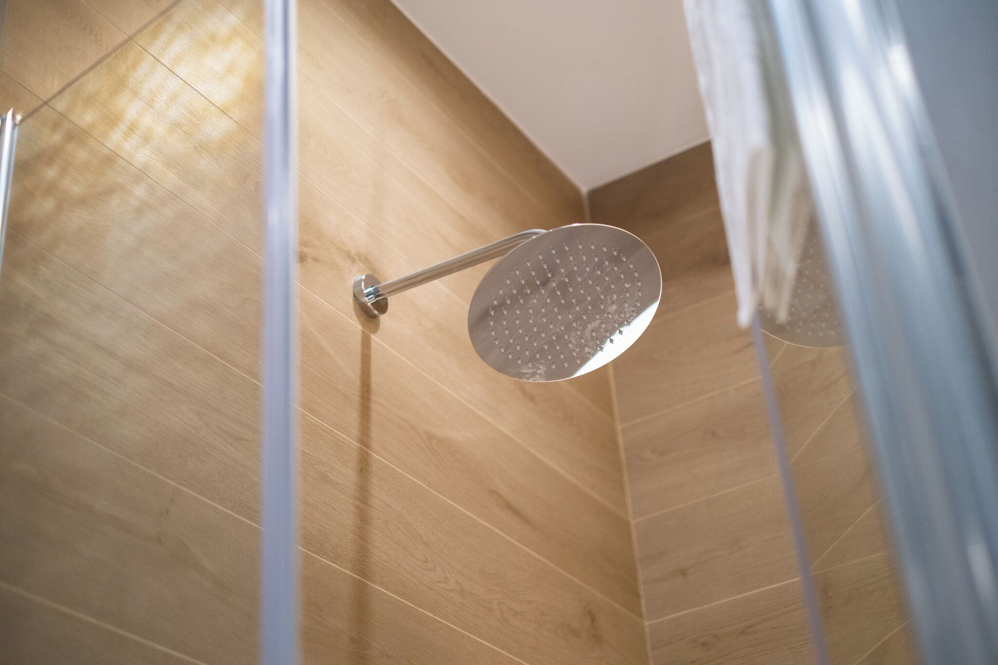 A shower with a handheld showerhead mounted on a wooden wall.