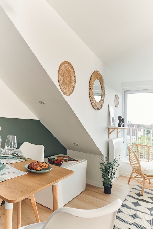 Un coin repas comprenant une table, des chaises, une plante en pot et des miroirs décoratifs fixés au mur.