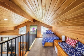 A wooden interior with a bed, a bench, and a staircase. - Olinca Ranch (Driftwood)