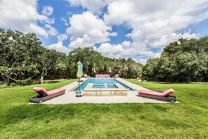 A swimming pool with a sunken seating area, surrounded by grass and trees. - Olinca Ranch (Driftwood)