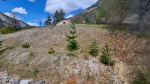 Un paysage montagneux à la végétation clairsemée, avec un petit bâtiment.