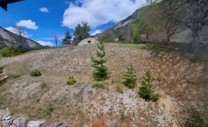Eine gebirgige Landschaft mit kargen Pflanzen und einem kleinen Gebäude.
