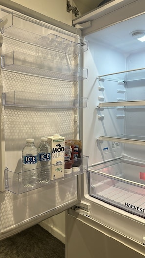 An open refrigerator with clear shelves, a water dispenser, and a milk carton. - Peaceful 2BR Stay with Fast Reliable Wi-Fi (Kingston upon Hull)