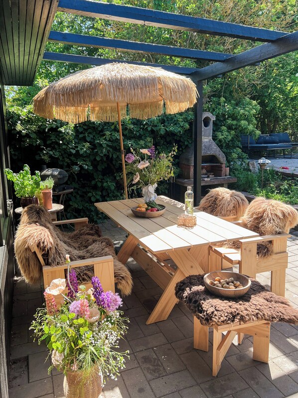Un comedor al aire libre de madera con una mesa, sillas y una parrilla.