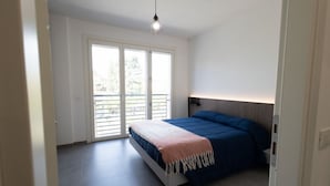 Una camera da letto con un letto, una lampada a soffitto e una porta scorrevole in vetro che dà su un balcone.