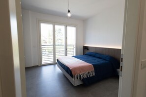 A bedroom with a bed, a ceiling light, and a sliding glass door leading to a balcony. - GuestHost - Cozy Apartment Pigneto Metro C (Roma)