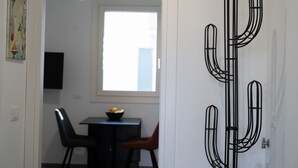 Una stanza con un tavolo da pranzo, sedie, un'opera d'arte nera e una finestra con vista.