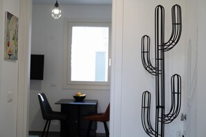 A room with a dining table, chairs, a black artwork, and a window with a view. - GuestHost - Cozy Apartment Pigneto Metro C (Roma)