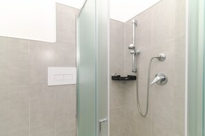 A modern shower with a glass door, a handheld showerhead, and a wall-mounted faucet. - Apartment 'Villino San Teodoro' with Private Terrace, Garden and Air Conditioning (San Teodoro)
