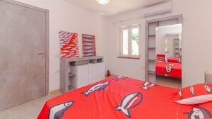 A bedroom with a bed, a wardrobe, a desk, and a window. - Apartment 'Villino San Teodoro' with Private Terrace, Garden and Air Conditioning (San Teodoro)