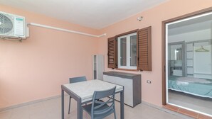 A compact room with a kitchenette, a dining table, and a sliding glass door leading to a bathroom. - Private Luxury Room in Central San Teodoro with Private Terrace, Garden, and Air Conditioning (San Teodoro)