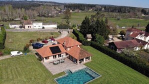 Ein Wohnhaus mit Swimmingpool, überdachter Terrasse und Garage.