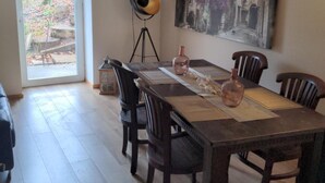 Un comedor con una mesa de madera, sillas, una lámpara de pie y un cuadro en la pared.