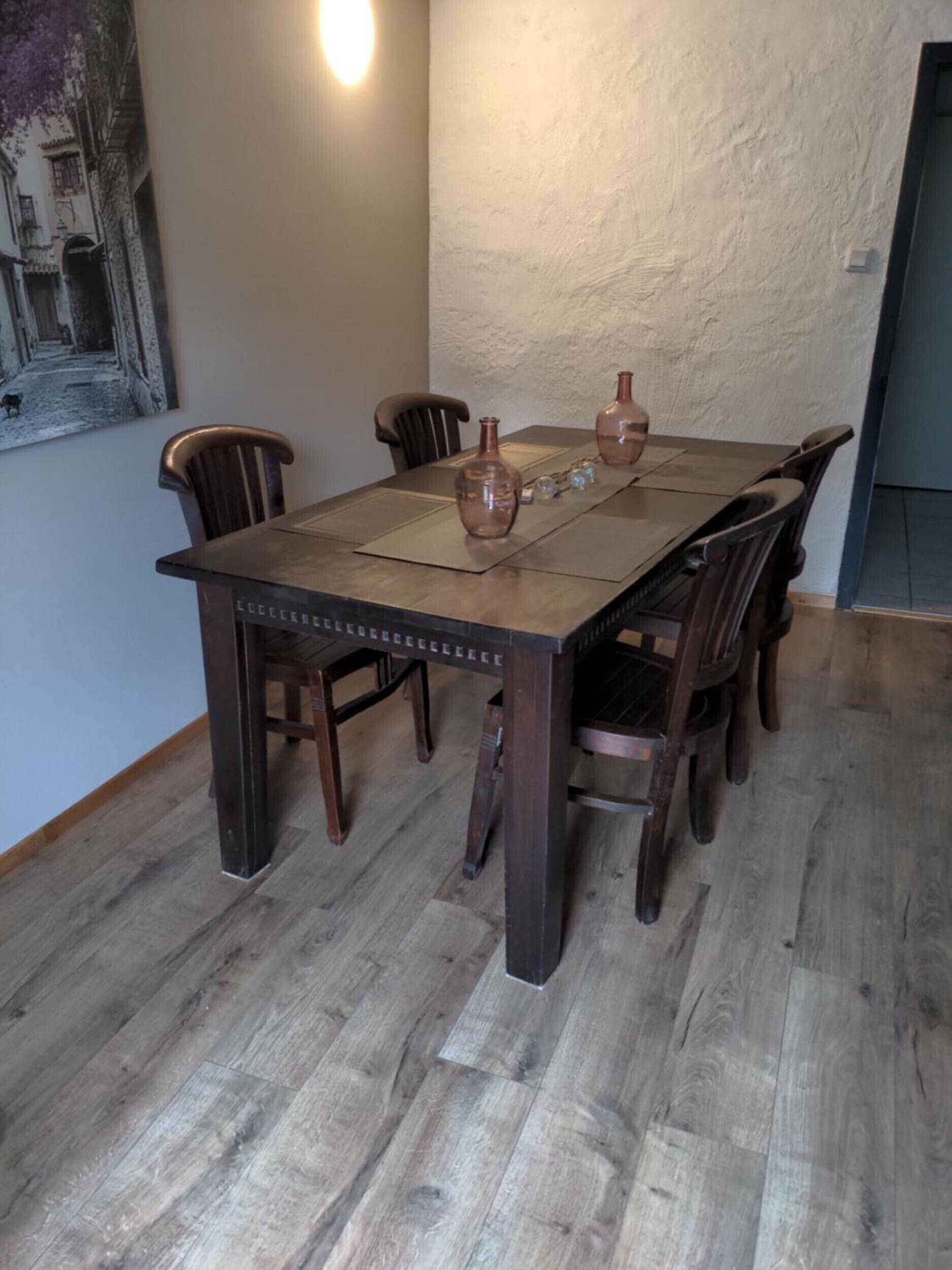 A dining table with six chairs, a vase, and a candle on a textured wall.