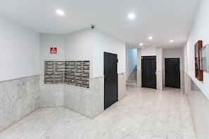 Ein Flur mit Briefkasten, schwarzen Türen und einer Treppe.