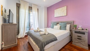 Un dormitorio con cama, escritorio, silla y ventana con cortinas.