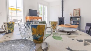 Una mesa de comedor con varios objetos de cerámica, un televisor al fondo y una chimenea.