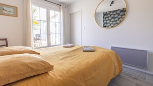 Un dormitorio con cama, un espejo redondo, un radiador y una ventana con cortinas.