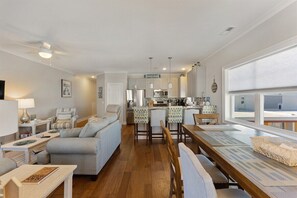 Ein modernes Wohnzimmer mit einer Couch, einem Esstisch und einer Küchenzeile im Hintergrund.
