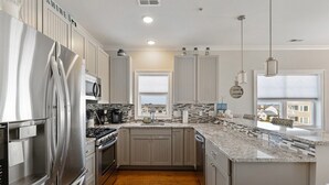 Una cucina moderna con elettrodomestici in acciaio inossidabile, un piano di lavoro in granito e vista su una zona residenziale.