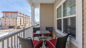 Un balcone con tavolo e sedie, vista su un edificio di fronte e cielo sereno.