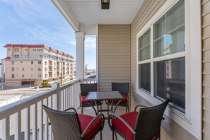 Ein Balkon mit Tisch und Stühlen, Blick auf ein gegenüberliegendes Gebäude und einen klaren Himmel.