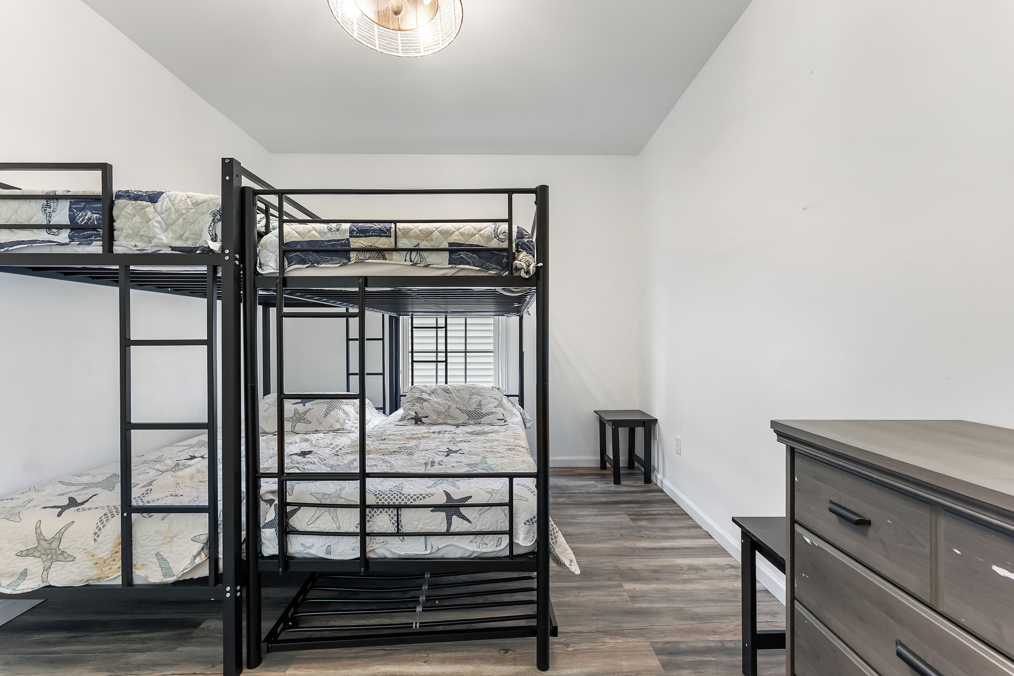 A bunk bed room with a desk and dresser.