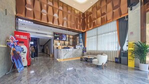Un vestíbulo de hotel con mostrador de recepción, zona de estar y un ventanal grande.
