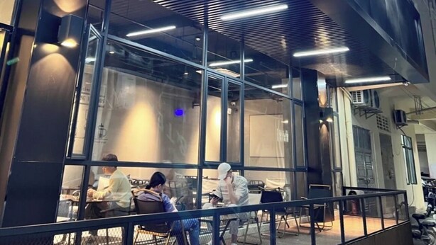 Una cafetería de diseño moderno, con un letrero llamativo y amplias ventanas.