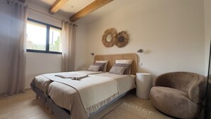 A bedroom with a bed, a chair, a bedside lamp, and a window with curtains. - Charming sheepfold, comfortable and ideally located (Figari)